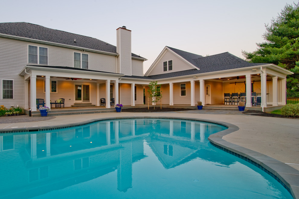Esempio di una grande piscina american style a "C" dietro casa con una dépendance a bordo piscina e pavimentazioni in pietra naturale