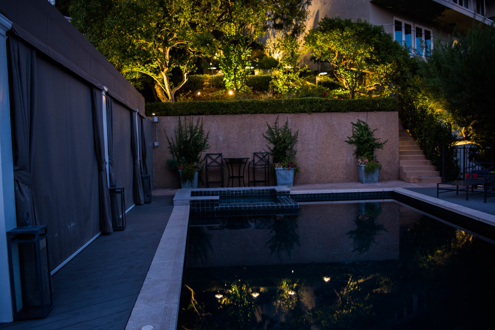 Esempio di una piscina monocorsia minimalista rettangolare di medie dimensioni e dietro casa con una vasca idromassaggio e pavimentazioni in cemento