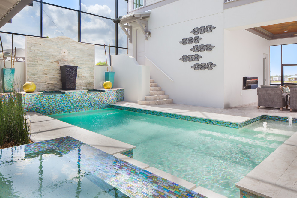 Esempio di una grande piscina monocorsia tropicale rettangolare dietro casa con fontane e pavimentazioni in pietra naturale