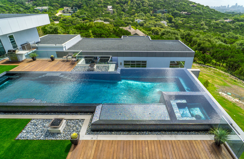 Ejemplo de piscina con fuente infinita minimalista grande a medida en patio con entablado