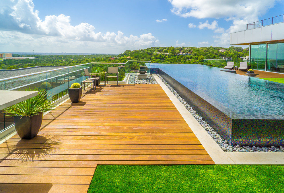 Example of a large minimalist courtyard custom-shaped infinity pool fountain design in Austin with decking