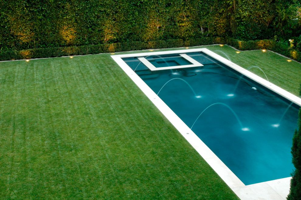 Modelo de piscinas y jacuzzis alargados grandes rectangulares en patio trasero con adoquines de piedra natural