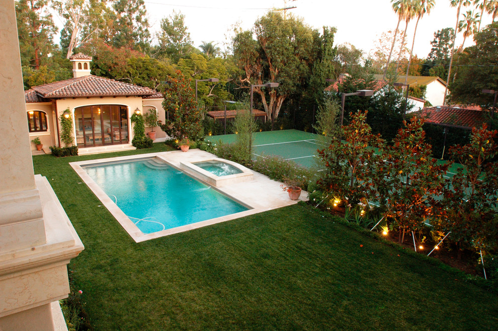 Esempio di un'ampia piscina monocorsia chic rettangolare dietro casa con una dépendance a bordo piscina e pavimentazioni in pietra naturale