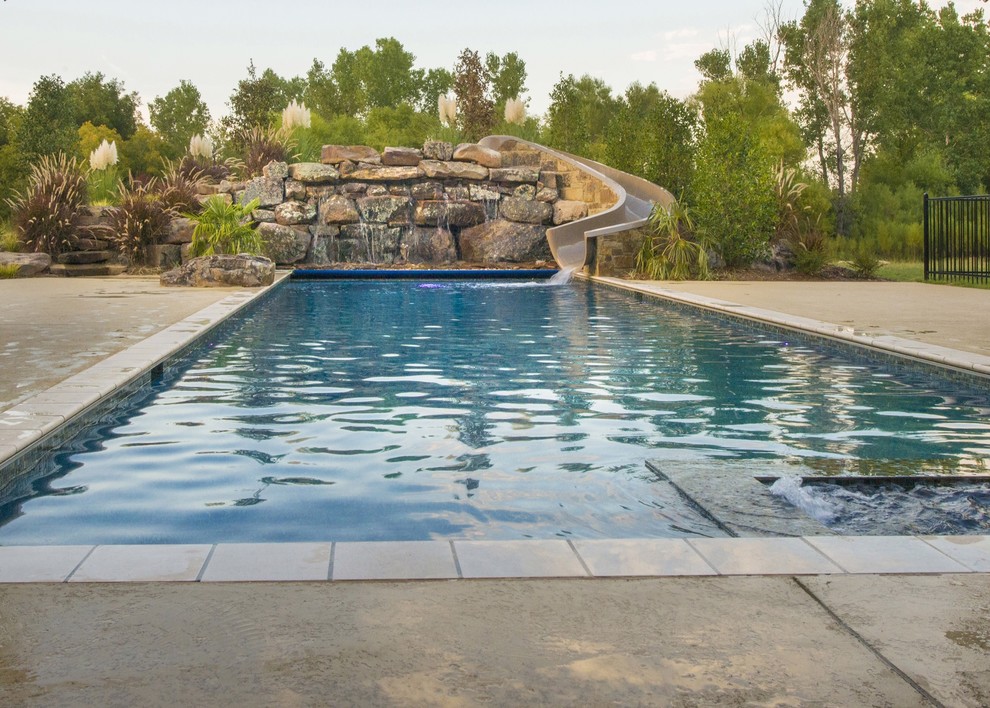 Réalisation d'une grande piscine naturelle et arrière minimaliste rectangle avec un point d'eau et du béton estampé.
