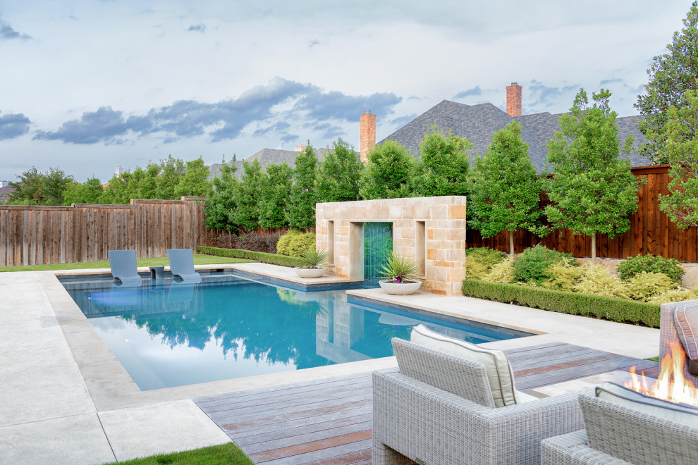 This is an example of a large modern back rectangular swimming pool in Dallas with decking.