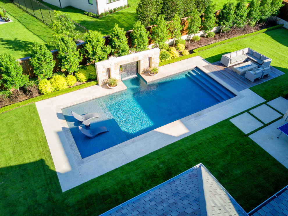 Réalisation d'une grande piscine arrière minimaliste rectangle avec une terrasse en bois.