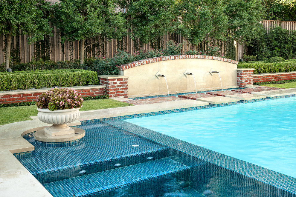 Ejemplo de piscina con fuente tradicional grande a medida en patio trasero con adoquines de piedra natural