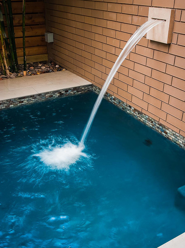 Immagine di una piscina monocorsia contemporanea rettangolare di medie dimensioni e dietro casa con pavimentazioni in cemento e fontane