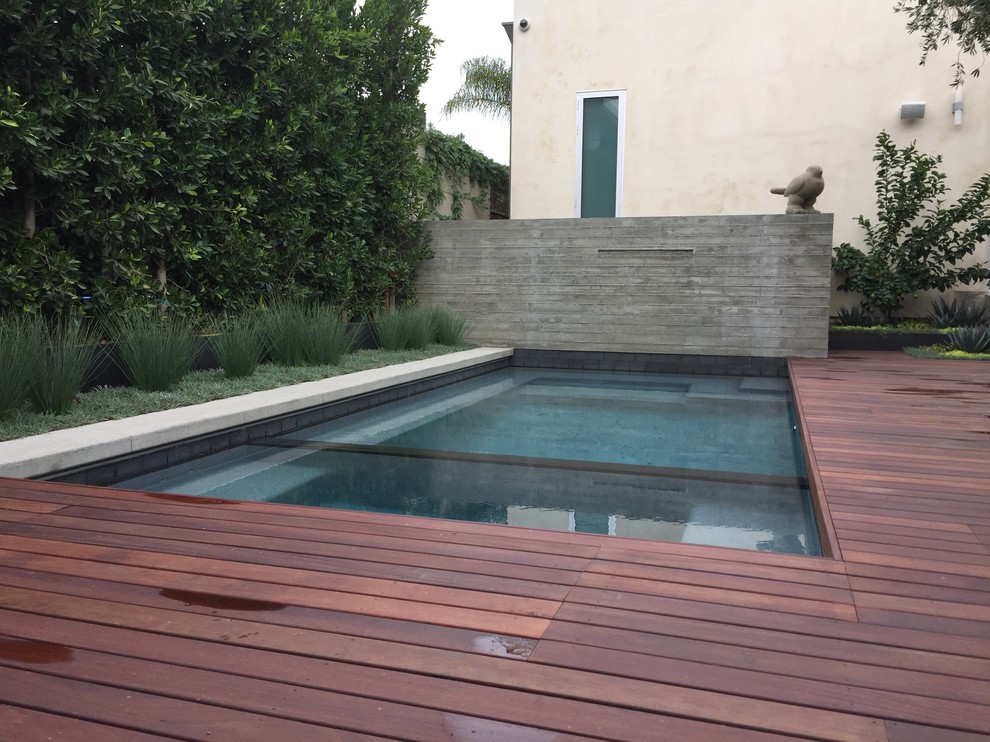 На фото: спортивный, прямоугольный бассейн среднего размера на заднем дворе в стиле модернизм с джакузи и настилом с