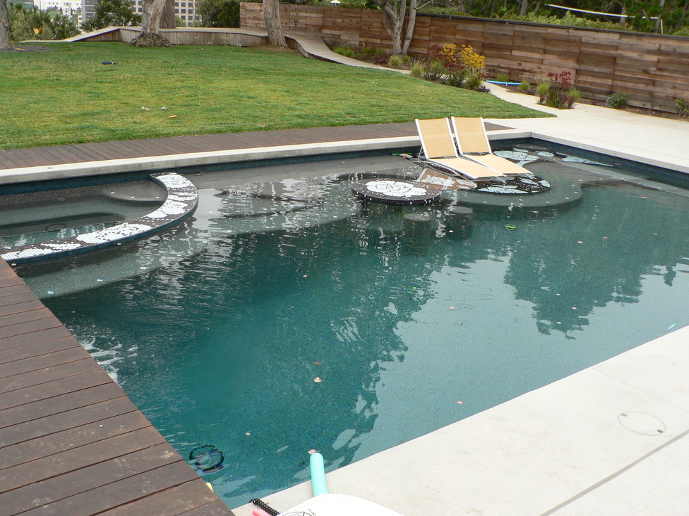 Aménagement d'une grande piscine arrière contemporaine rectangle avec une dalle de béton et un bain bouillonnant.