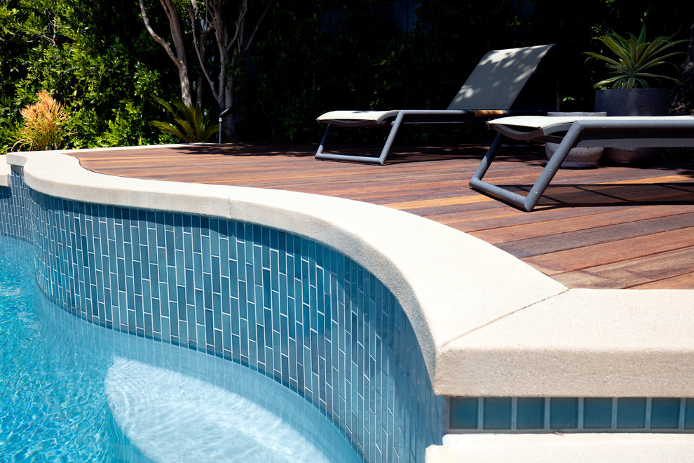 Cette photo montre une piscine naturelle et arrière rétro de taille moyenne et sur mesure avec une terrasse en bois.