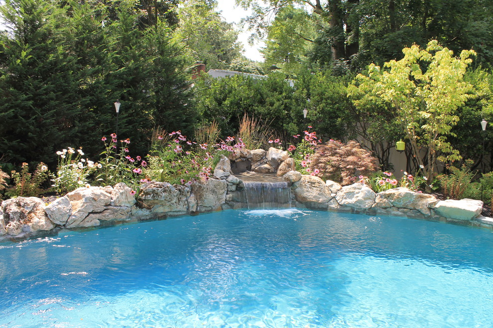 Foto di una piscina naturale chic personalizzata di medie dimensioni e dietro casa con fontane e pavimentazioni in pietra naturale