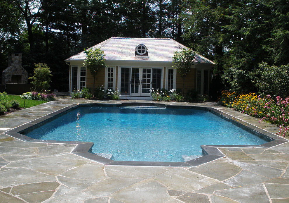 Ejemplo de casa de la piscina y piscina alargada clásica de tamaño medio rectangular en patio trasero con adoquines de piedra natural