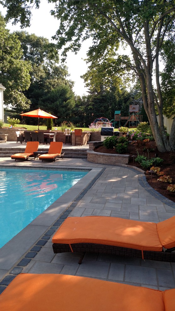Immagine di una grande piscina monocorsia design rettangolare dietro casa con pavimentazioni in cemento