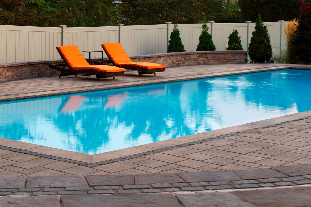 Foto de piscina alargada tradicional grande rectangular en patio trasero con adoquines de hormigón