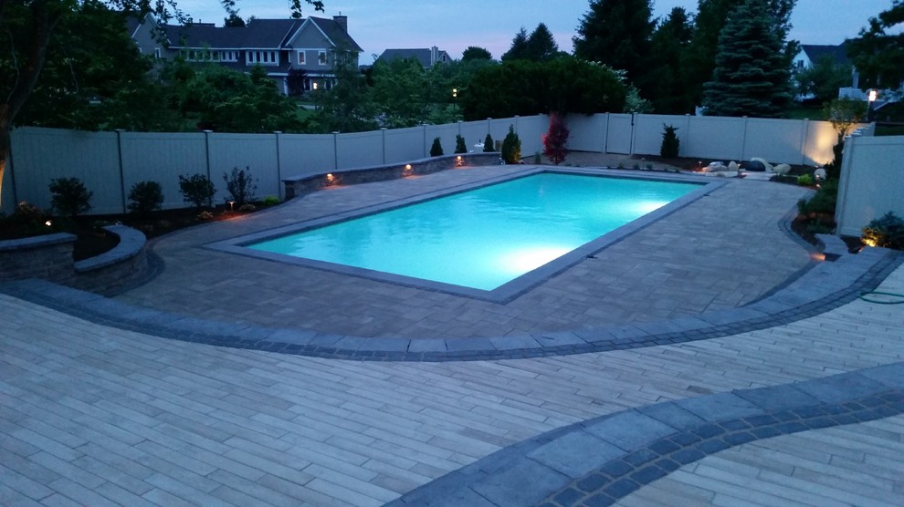 This is an example of a large nautical back rectangular natural swimming pool in Boston with a water feature and concrete paving.