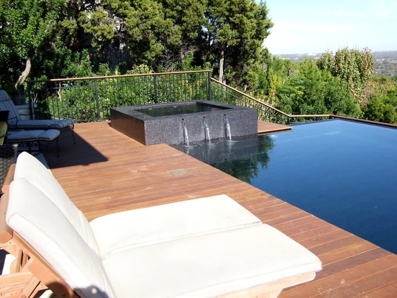 This is an example of a medium sized contemporary back rectangular infinity swimming pool in Austin with a water feature and decking.