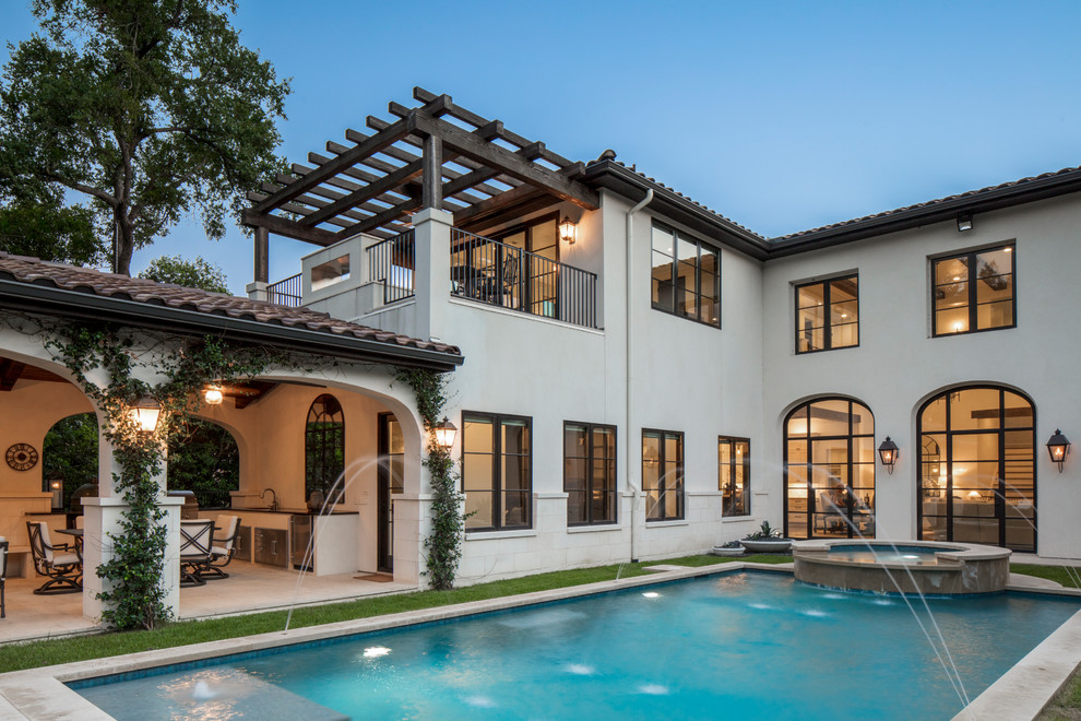 This is an example of a large mediterranean back rectangular swimming pool in Austin with a water feature and tiled flooring.