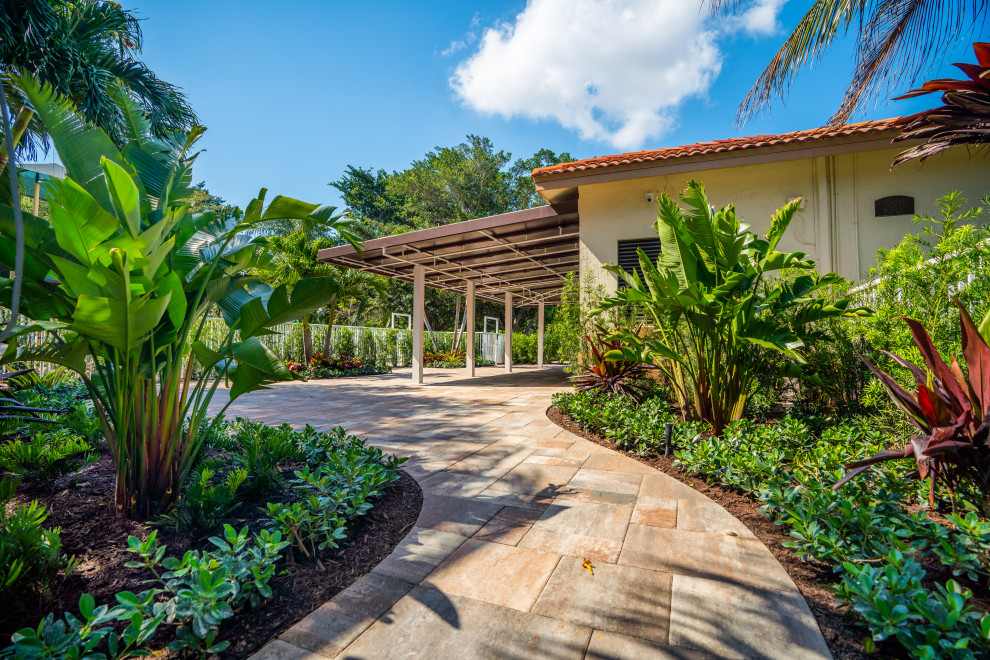 Immagine di una grande piscina tropicale personalizzata in cortile con paesaggistica bordo piscina e pavimentazioni in cemento