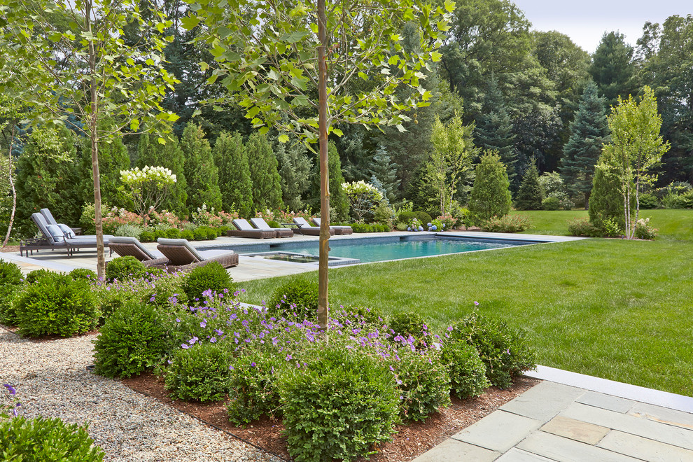Ispirazione per una grande piscina naturale chic rettangolare dietro casa con una vasca idromassaggio e pavimentazioni in pietra naturale