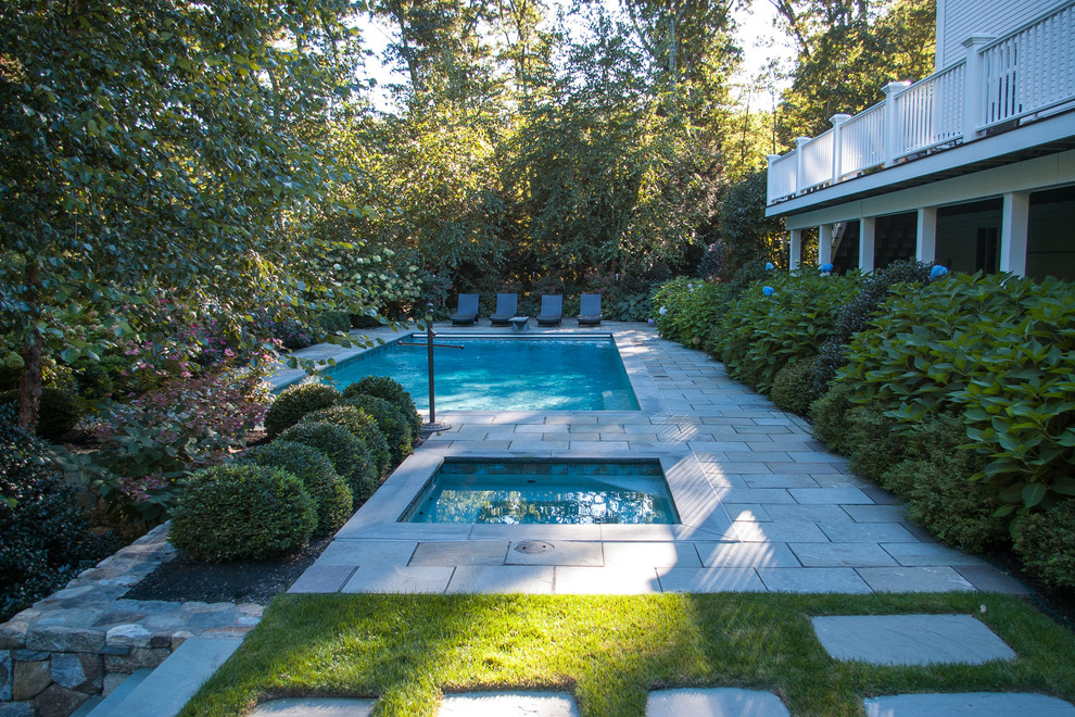 Idées déco pour une grande piscine arrière classique rectangle avec un bain bouillonnant et des pavés en pierre naturelle.