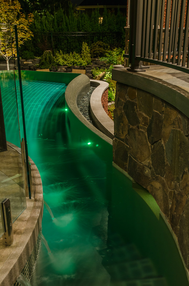 Свежая идея для дизайна: бассейн-инфинити среднего размера, произвольной формы на заднем дворе в современном стиле с фонтаном и покрытием из каменной брусчатки - отличное фото интерьера