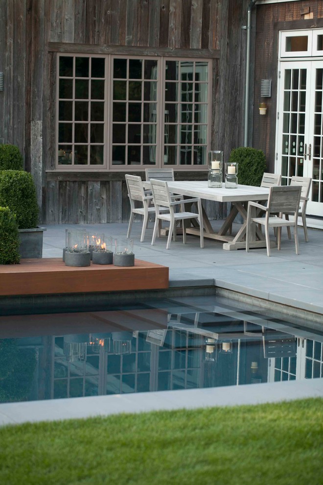 Immagine di una piscina monocorsia minimal rettangolare di medie dimensioni e dietro casa con fontane e lastre di cemento