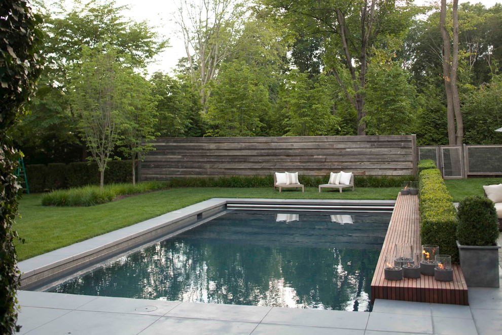 Diseño de piscina con fuente alargada de estilo de casa de campo de tamaño medio rectangular en patio trasero con losas de hormigón