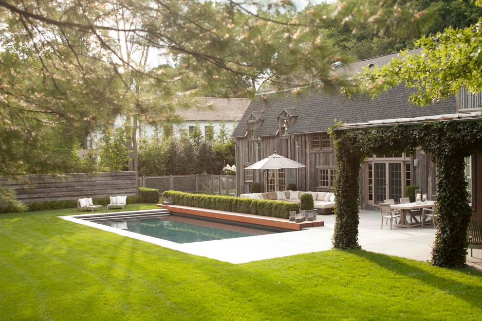 Immagine di una piscina monocorsia rettangolare di medie dimensioni e dietro casa con lastre di cemento
