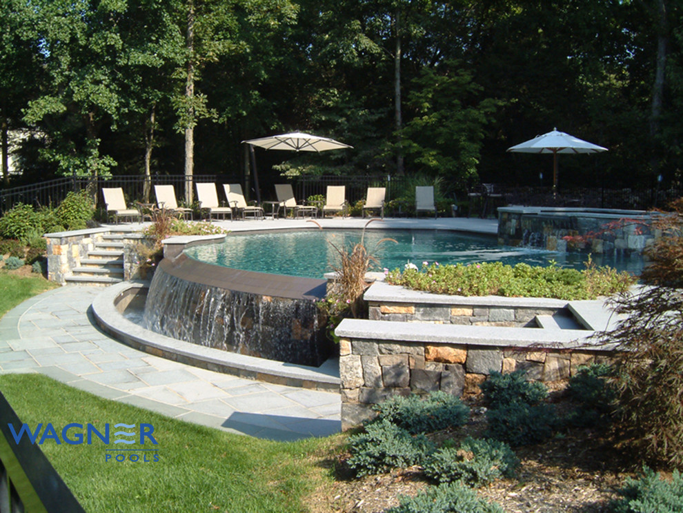Diseño de piscina con fuente infinita clásica grande a medida en patio trasero con adoquines de piedra natural