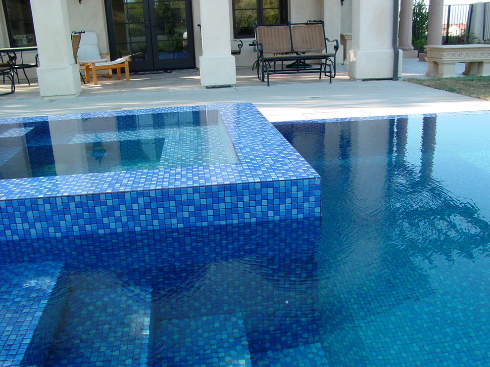 Foto de piscinas y jacuzzis infinitos modernos de tamaño medio en forma de L en patio trasero con losas de hormigón