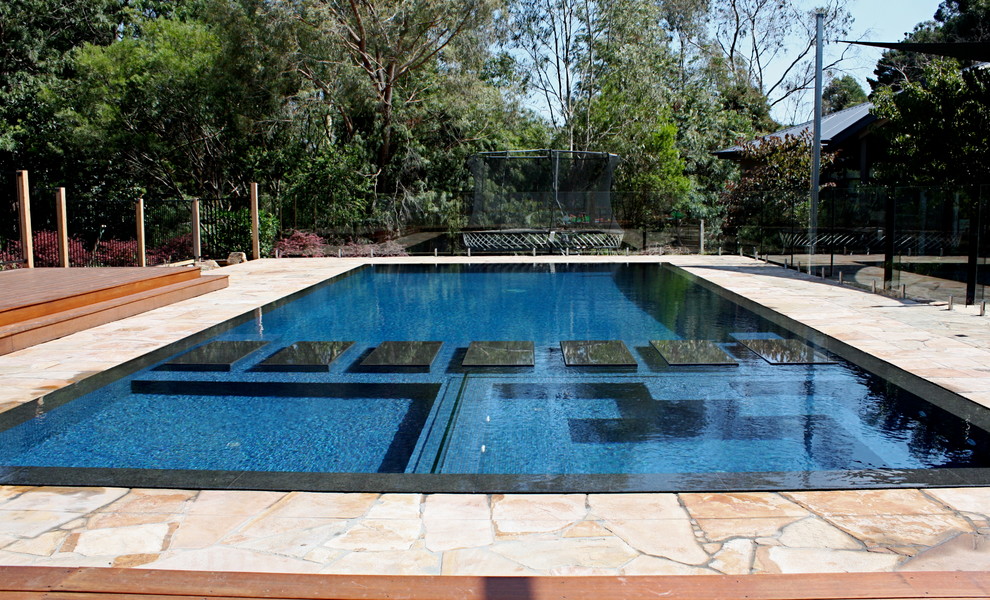 Foto på en stor funkis pool på baksidan av huset, med naturstensplattor