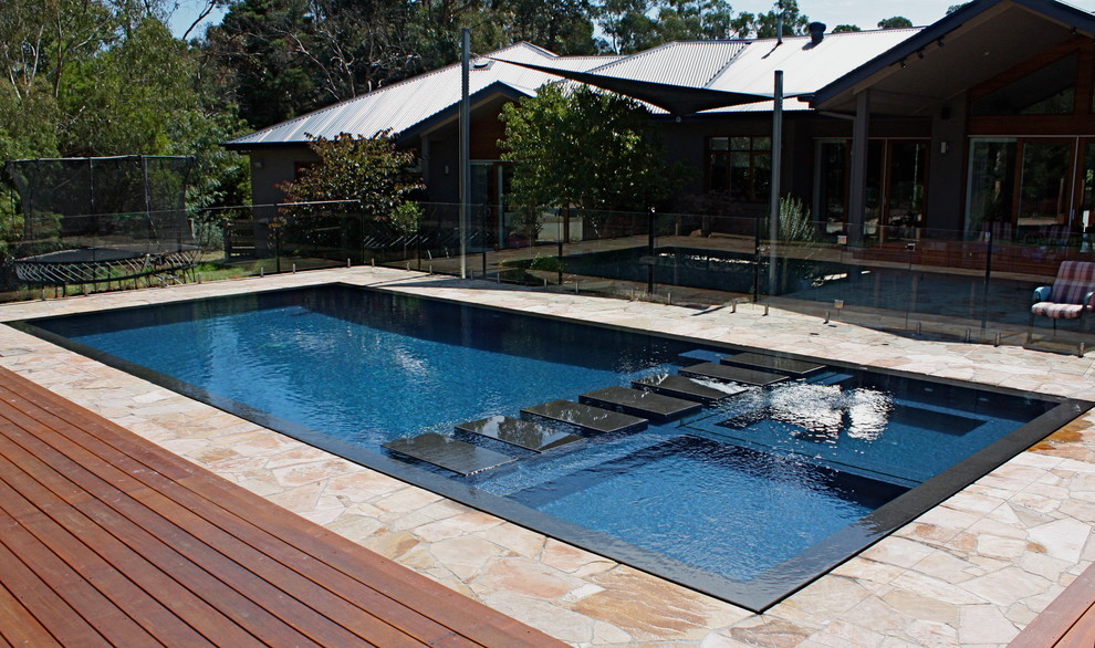 Foto di una grande piscina moderna rettangolare dietro casa con pavimentazioni in pietra naturale