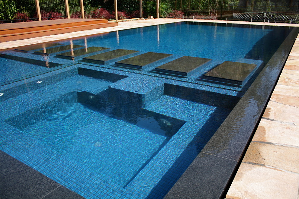 Idée de décoration pour une grande piscine arrière minimaliste rectangle avec des pavés en pierre naturelle.