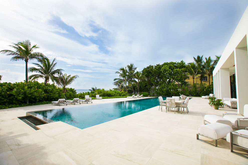 Geräumiger Moderner Infinity-Pool hinter dem Haus in rechteckiger Form mit Natursteinplatten in Miami
