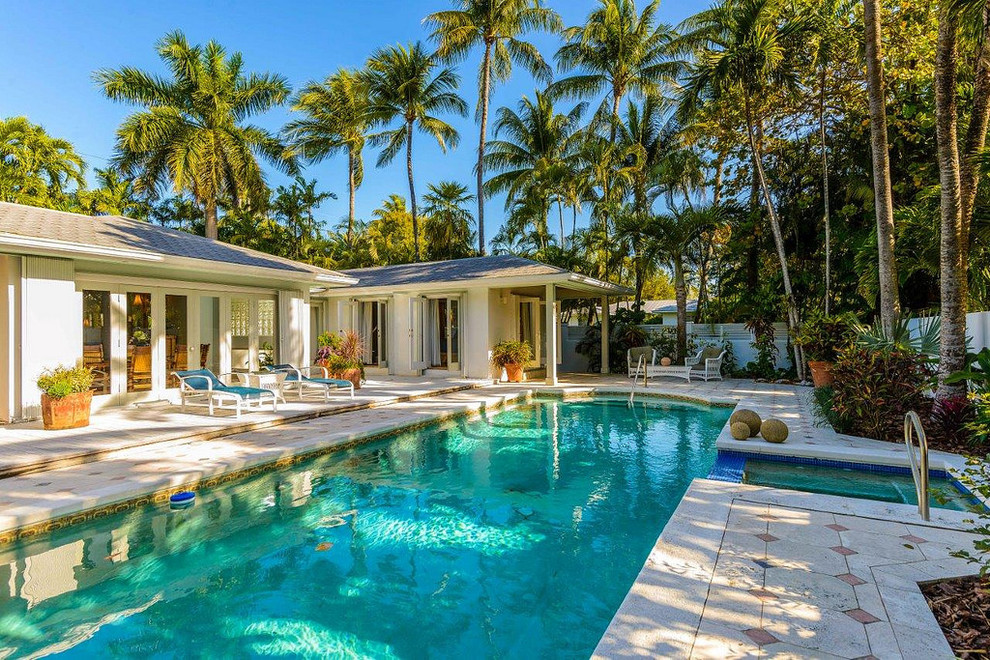 Immagine di una grande piscina tropicale rettangolare dietro casa con una vasca idromassaggio e pavimentazioni in pietra naturale