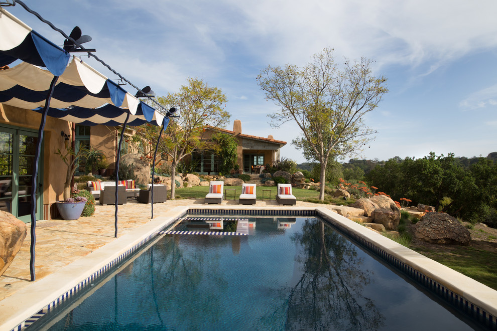 Ejemplo de piscinas y jacuzzis alargados de estilo americano grandes rectangulares en patio trasero con adoquines de piedra natural