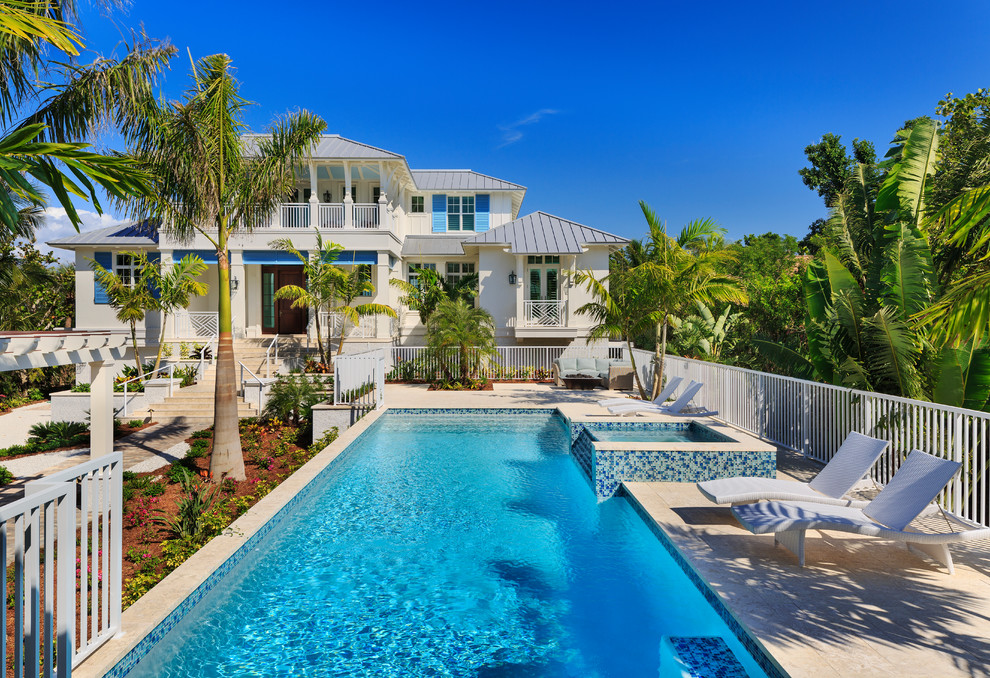 Ispirazione per una grande piscina monocorsia tropicale rettangolare davanti casa con una vasca idromassaggio e pavimentazioni in pietra naturale