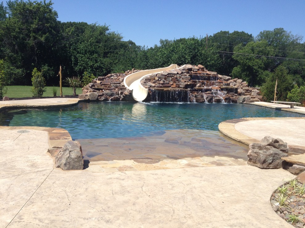 Idee per un'ampia piscina monocorsia stile marino personalizzata dietro casa con cemento stampato e un acquascivolo