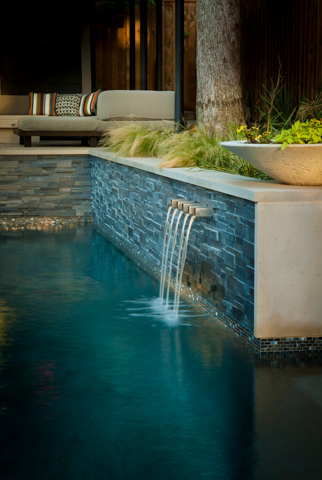Foto de piscina moderna de tamaño medio en forma de L en patio trasero con losas de hormigón