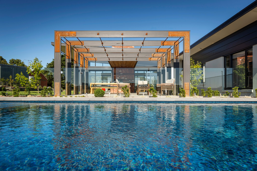 Immagine di una grande piscina a sfioro infinito design rettangolare dietro casa con pavimentazioni in pietra naturale