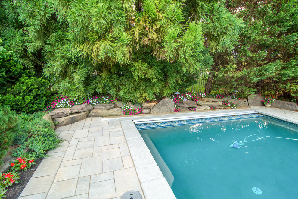 Exemple d'un grand couloir de nage arrière chic rectangle avec un bain bouillonnant et une terrasse en bois.