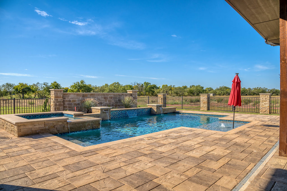 Foto de piscina con fuente actual de tamaño medio rectangular en patio trasero con adoquines de hormigón