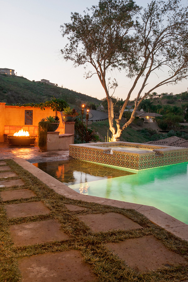 Aménagement d'une grande piscine naturelle et arrière méditerranéenne rectangle avec un bain bouillonnant et du carrelage.