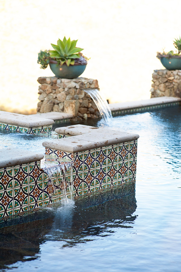 На фото: большой естественный, прямоугольный бассейн на заднем дворе в средиземноморском стиле с джакузи и мощением тротуарной плиткой с