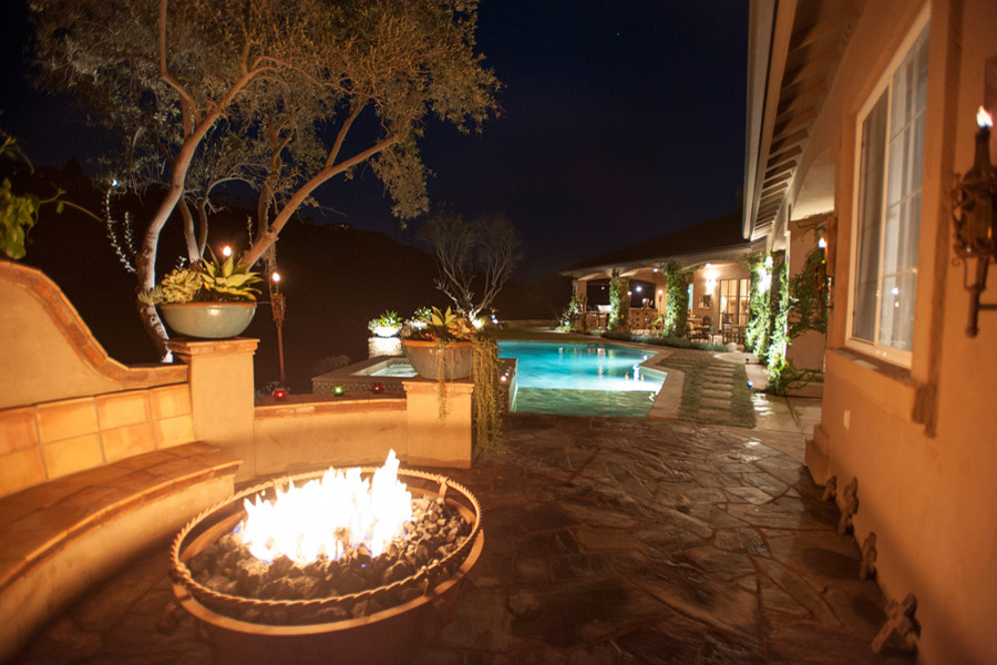 На фото: большой естественный, прямоугольный бассейн на заднем дворе в средиземноморском стиле с джакузи и покрытием из плитки с