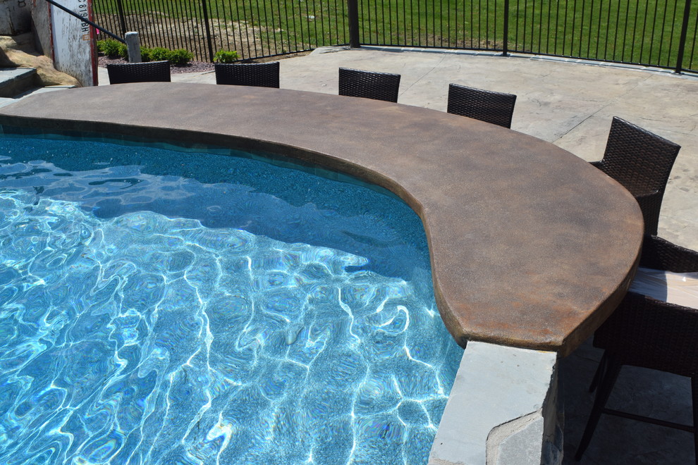 Immagine di un'ampia piscina classica personalizzata dietro casa con un acquascivolo e cemento stampato