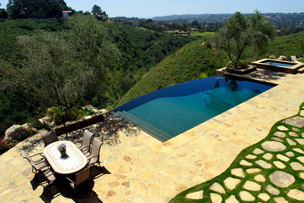 Ispirazione per una piscina a sfioro infinito mediterranea con pavimentazioni in pietra naturale