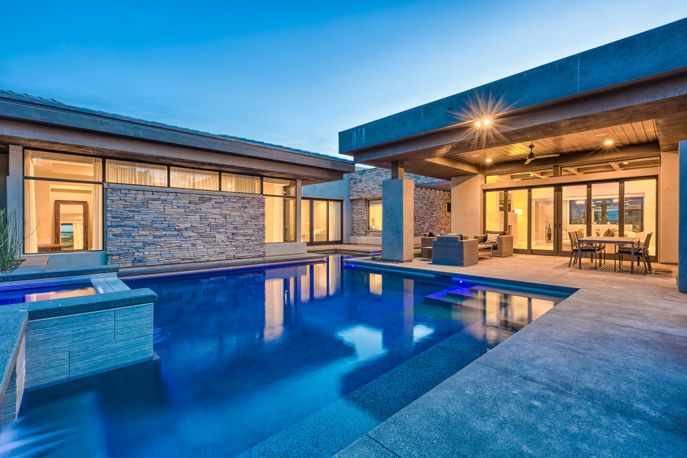 Ispirazione per una grande piscina monocorsia minimalista personalizzata dietro casa con una vasca idromassaggio e pavimentazioni in cemento