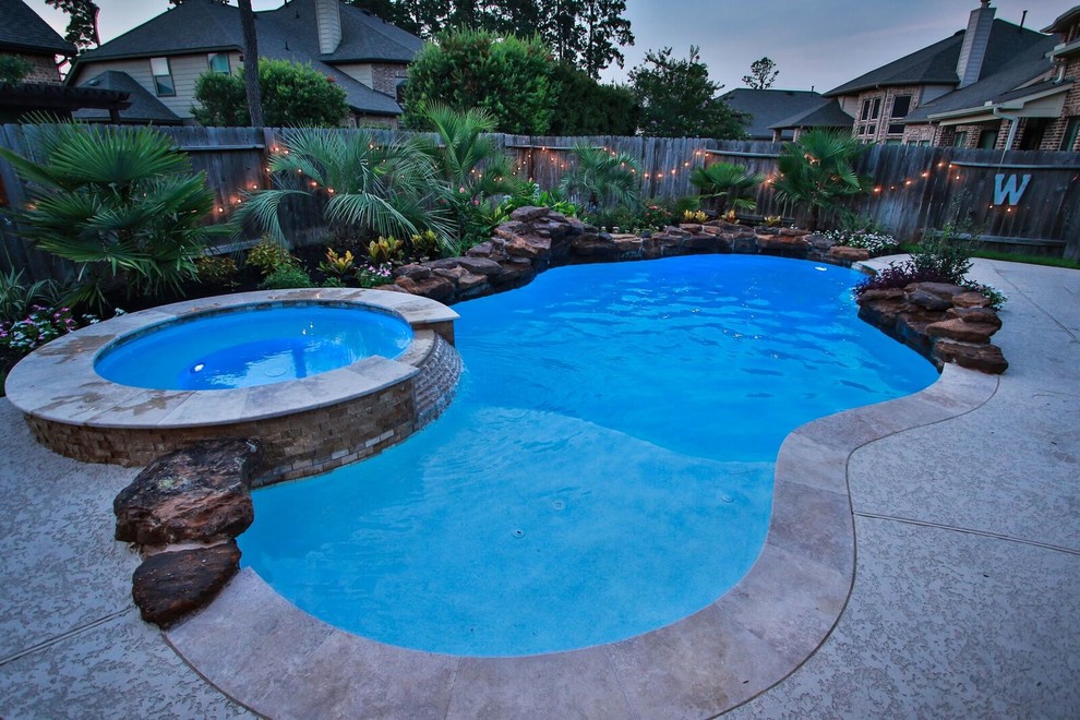 Design ideas for a large world-inspired back custom shaped natural hot tub in Houston with concrete paving.